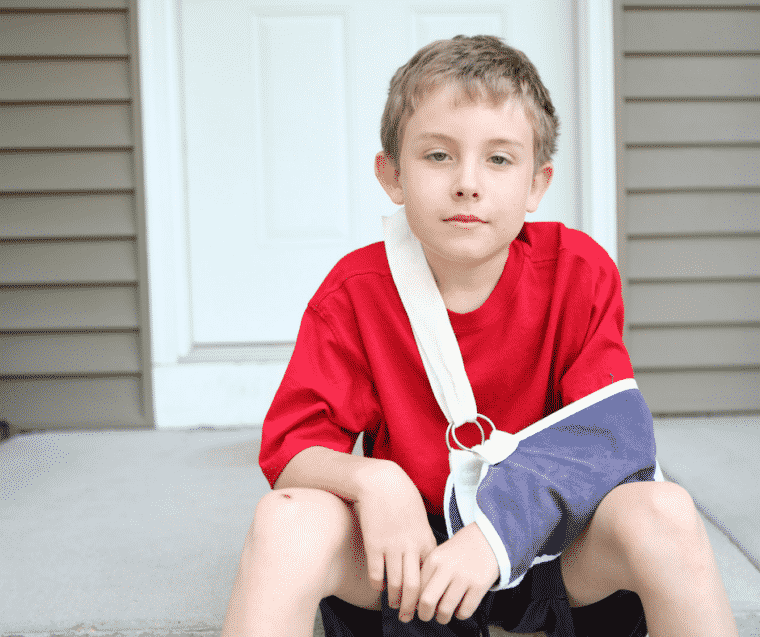 Boy sitting with broken arm, relaxed after accident