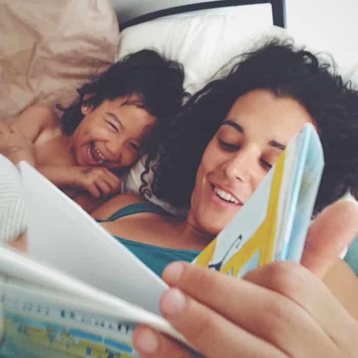 Mother reading a book with her laughing child