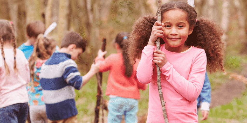 girl holding stick in adventure play setting in post about helping power struggles