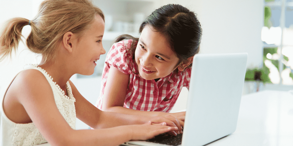 two girls laughing over a computer