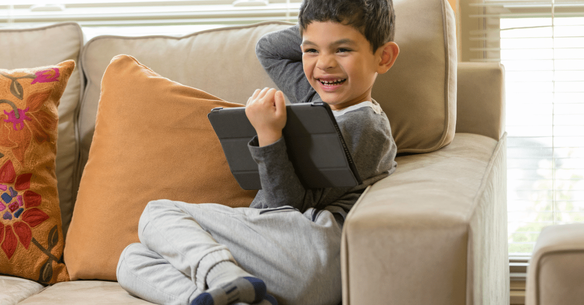 smiling boy on sofa using iPad