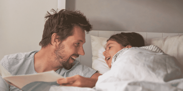 Père et enfant rient en écoutant une histoire à l'heure du coucher.