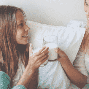 Image shows tween and her mom clinking glasses of milk in post about parenting tweens