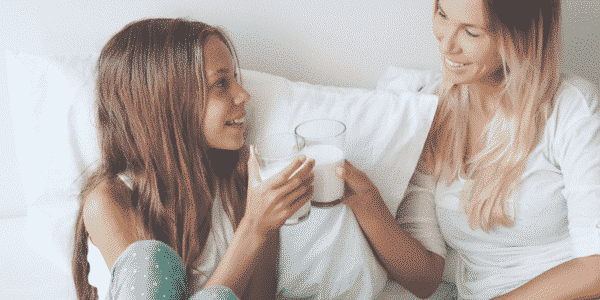 Image shows tween and her mom clinking glasses of milk in post about parenting tweens