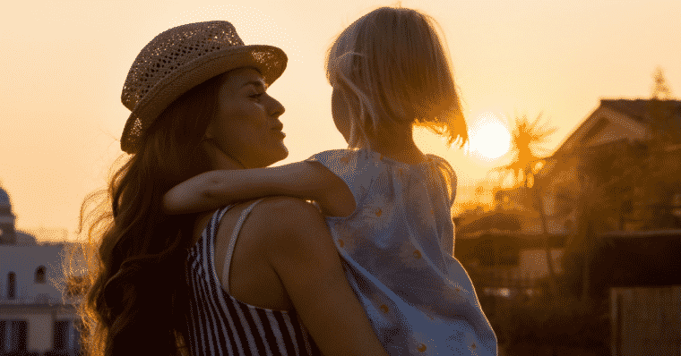 Mom holding child on vacation at sunset