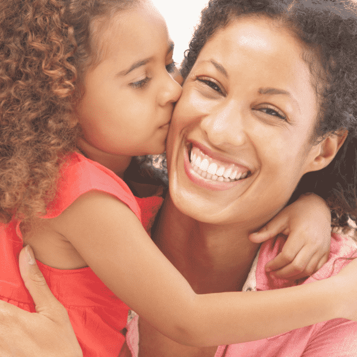 Mom laughing as daughter hugs her