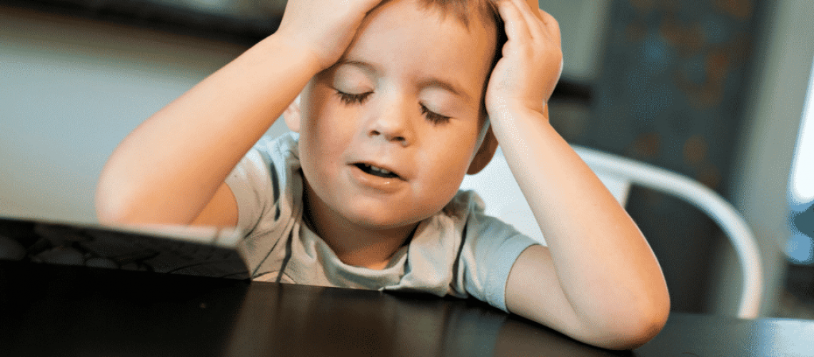 Boy with head in hands at dinner table in a post about handling picky eaters